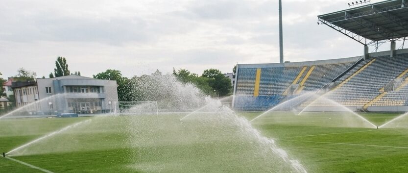 Versenkregner werfen Wasser in hohem Bogen über einen Sportplatz