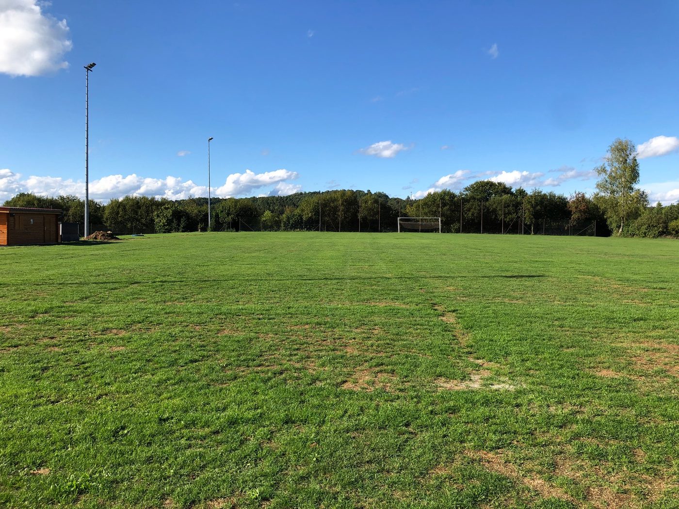 Rasenplatz eines Amateurvereins mit Bewässerung in der Erde unter blauem Himmel